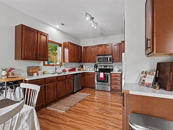 Kitchen featuring wood-finish flooring, white countertops, and stainless steel appliances