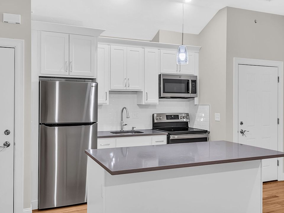 Kitchen with stainless steel refrigerator, electric range and microwave with view of entry door.