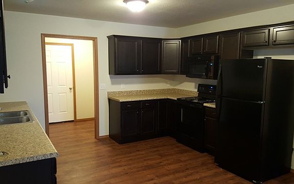 We provide your stove, microwave, dishwasher, and refrigerator. This kitchen has plenty of cabinet space and quick access to the laundry room and garage entry door.