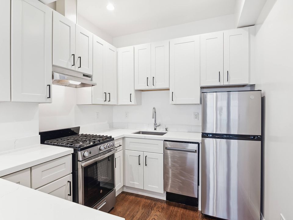 Kitchen with multiple cabinets, refrigerator, stove, range hood, and sink