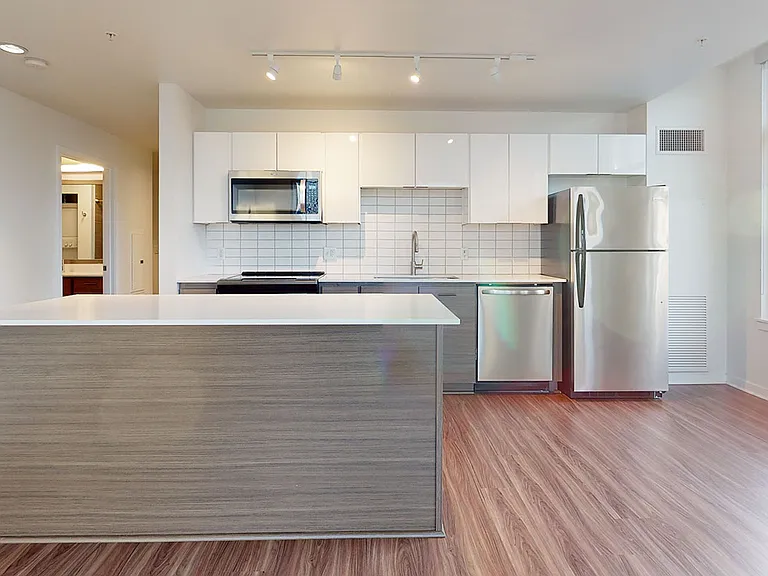 Apartment Kitchen with Stainless Steel Appliances, Quartz-style countertops and Wood-Style Flooring.
