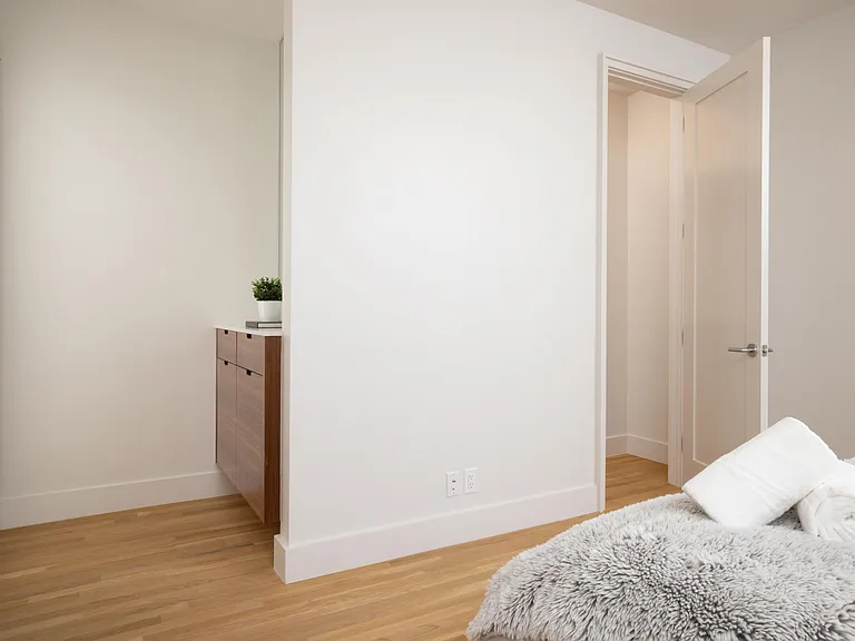 Primary bedroom showcases new artwork, a queen bed, floor-to-ceiling windows for natural light, and an attached bathroom for added convenience.