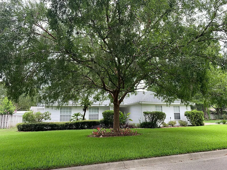 Front View showing large corner lot with beautiful landscaping. Professional lawn service provided by owner.
