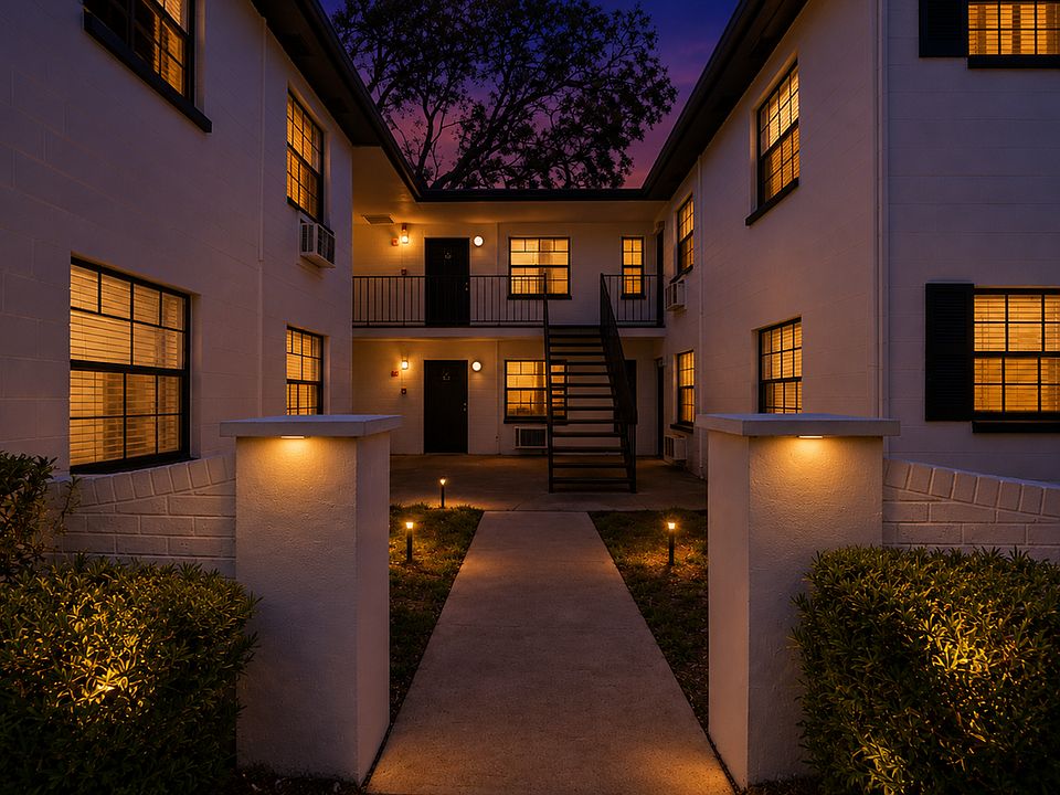 Charming apartment complex showcasing sunset ambiance and inviting exterior lighting, nestled amidst lush greenery and towering palms.