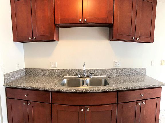 Kitchen counter is equipped with a deep stainless-steel sink and high arching kitchen faucet and plenty of power sockets.
