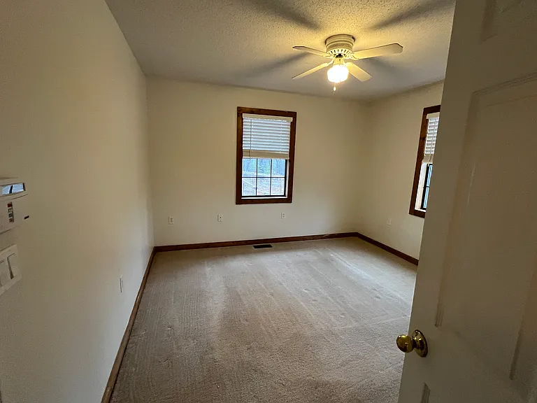 Main level bedroom includes:
Walk-in closet
Queen-sized room
Ceiling fan
Two single windows for natural light
Adjacent to shared bathroom with double vanity, bathtub, and separate shower.
