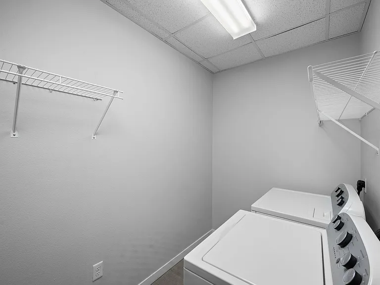 Modern laundry room with sleek white appliances and built-in shelving for storage solutions. Modern laundry room with sleek white appliances and built-in shelving for storage solutions.