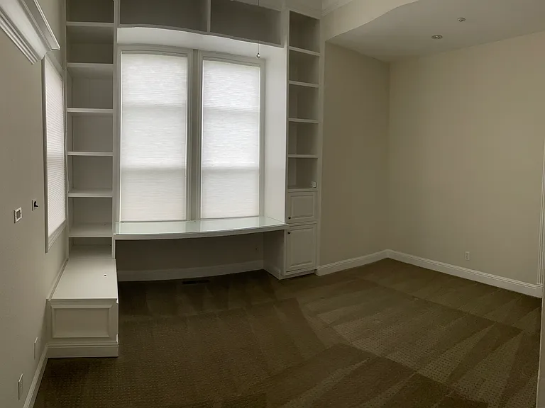 Large bedroom with built-in shelves (front yard facing windows) with shared bathroom