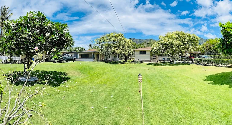 The rental home is located on the right side of the property. Enjoy a spacious, park-like setting with mature tropical landscaping, mountain views, and a peaceful neighborhood atmosphere just steps from Waimanalo Beach.