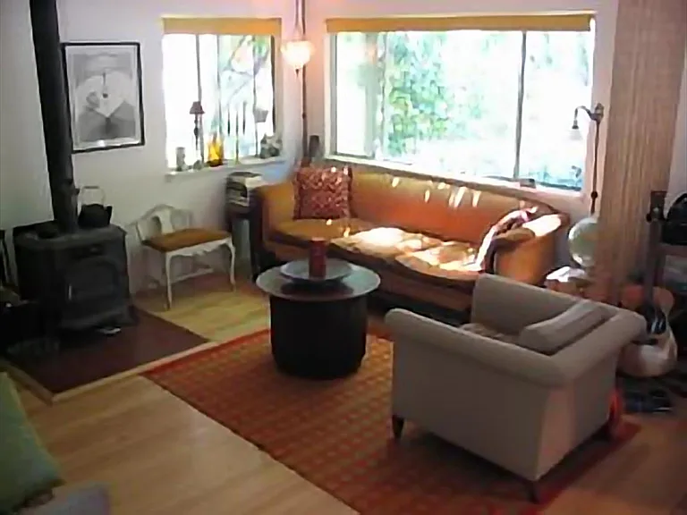 Living room with woodstove. Large windows to front gardens.