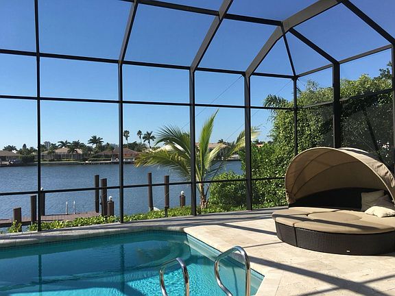 Lanai with large pool, hot tub, cabana, and ping pong table overlooking the bay