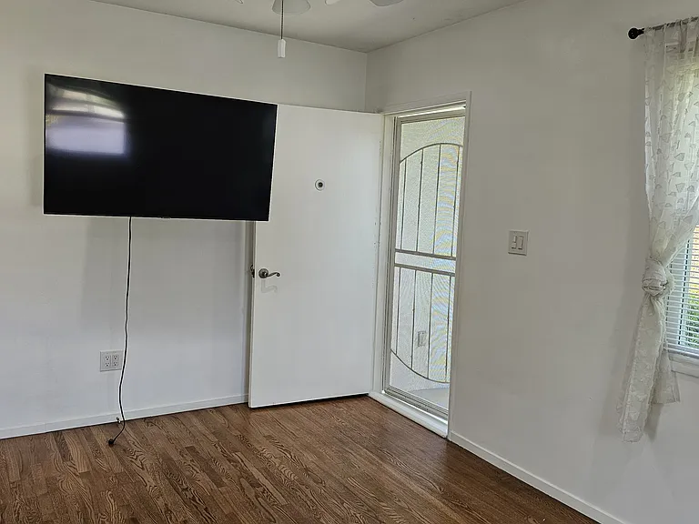 Front room, looking towards front door. TV is attached to wall, near front door.