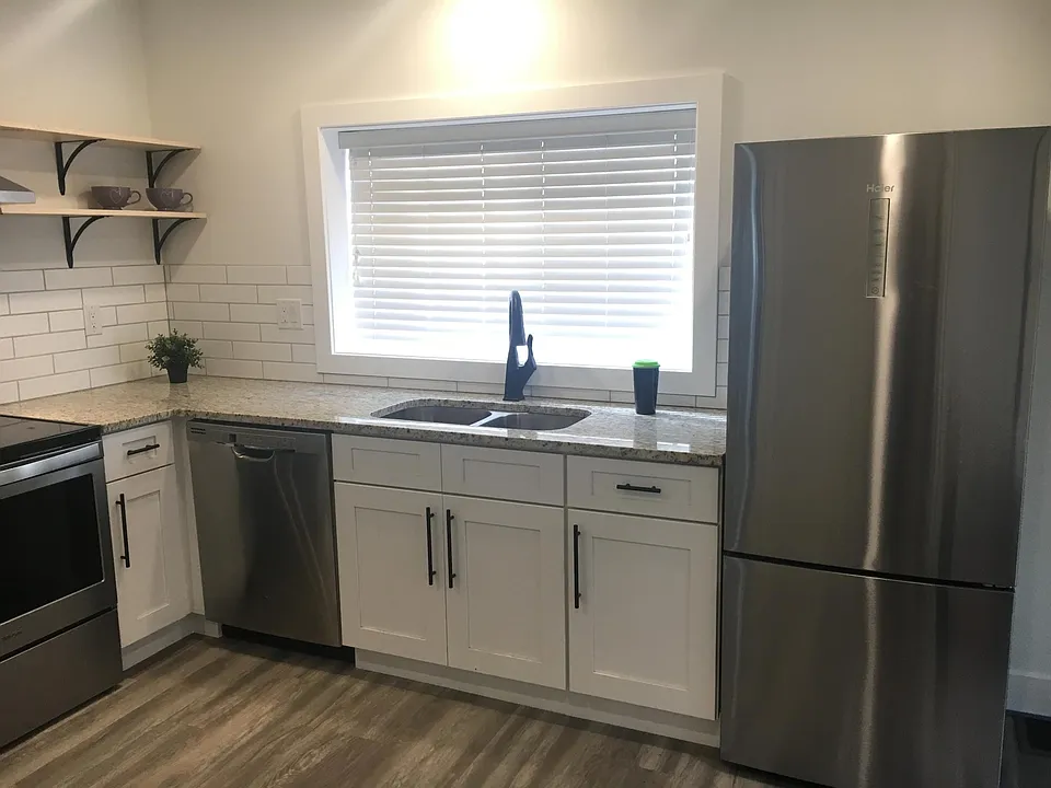 Kitchen with dual sink, D/W, refrigerator/freezer. All appliances are stainless steel.