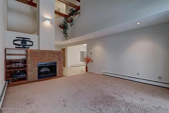 Living room with fireplace; tv rack over media shelves. Cathedral ceilings.