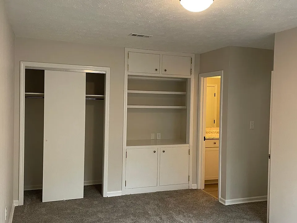master bedroom with one closet converted to TV/storage area, new cartpet