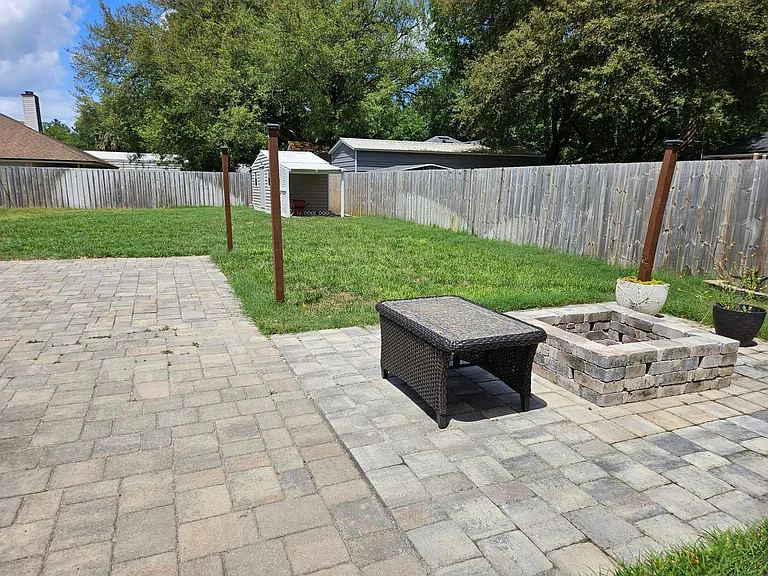 Paver patio with firepit extension, posts for solar lights, and connection for the included sun shade sail (Connects from the post to the connectors on the house, to provide a sun shade area that can be removed during inclement weather.)