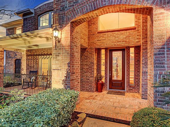 Covered Front porch and entry paved with brick. So many beautiful details including arched windows and custom iron front railing.