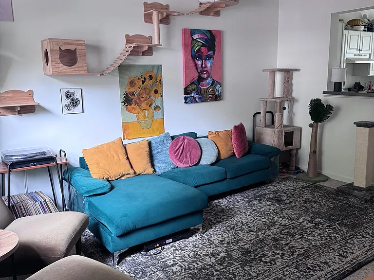 Spacious living room with a large sectional, wall art display, and an open pass-through to the kitchen for easy hosting.