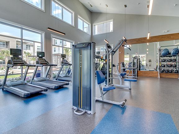 The fitness center is drenched in natural light and overlooks the pool