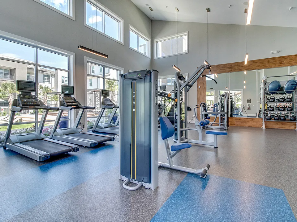 The fitness center is drenched in natural light and overlooks the pool