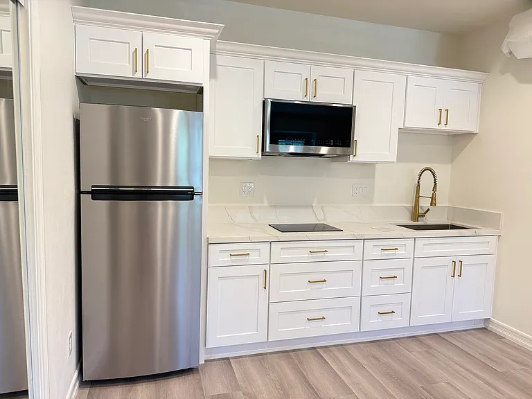 Modern kitchenette with quartz countertops, custom cabinetry, a brand-new Whirlpool refrigerator, an LG microwave, and ample storage.