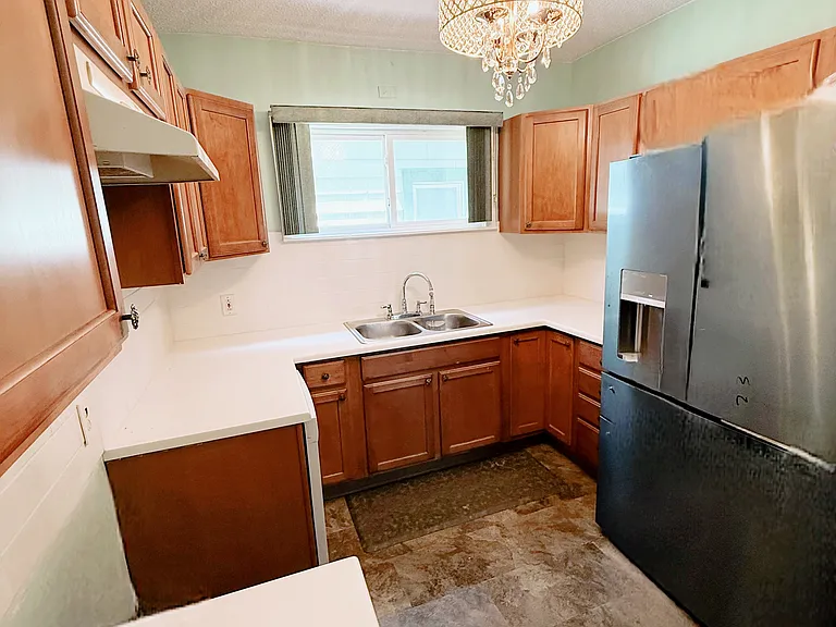 Kitchen features stainless steel stove and frig, a dish washer, modern countertops, backsplash, and a beautiful chandelier light fixture.