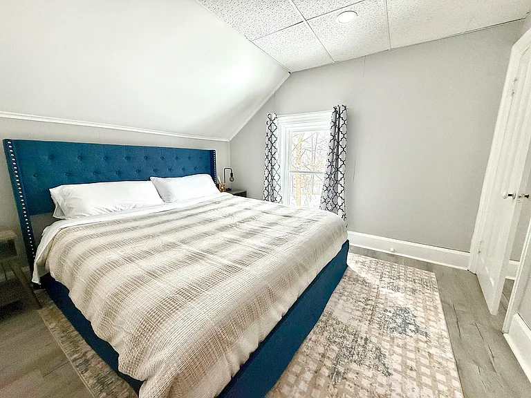 This spacious secondary bedroom features a king-size bed, filled with natural light and equipped with black-out shades for a restful, comfortable retreat.