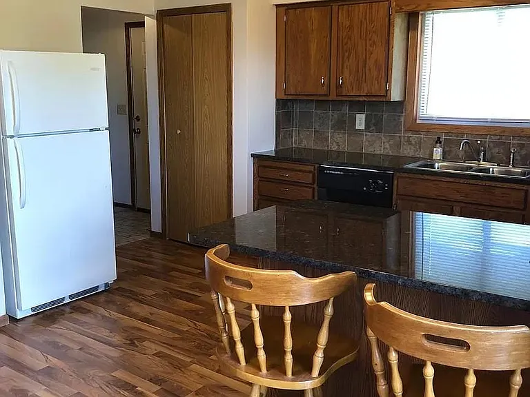 Kitchen features granite countertops, laminate floors, and tile backsplash