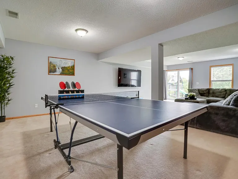 Spacious basement family room with huge sectional sofa, big screen TV, and Ping pong table for family entertainment