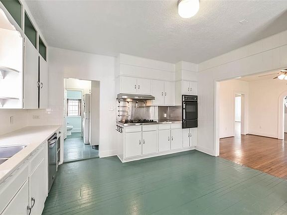 Updated kitchen with stainless gas range enhanced by a pop of color on the original hardwood floors.