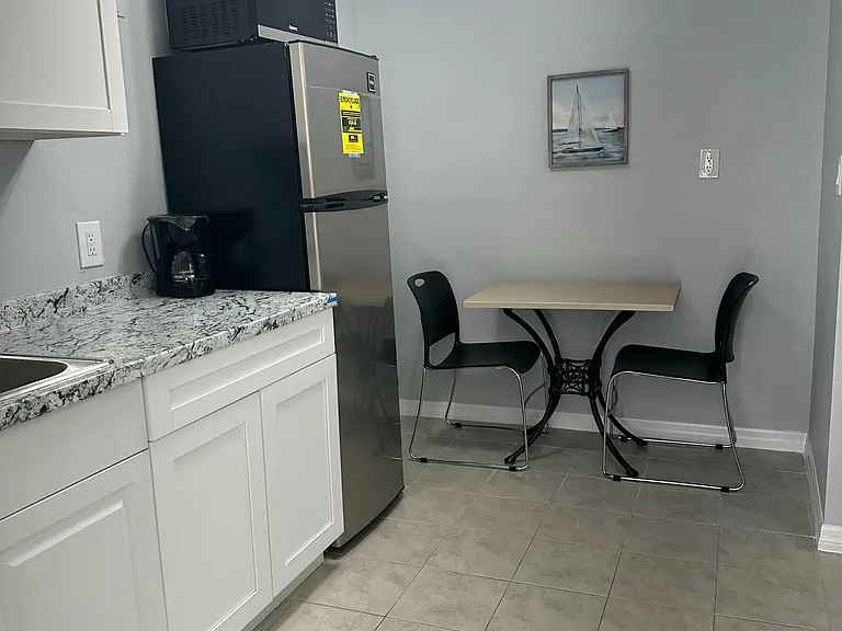 Eat-in kitchen nook with granite-look counters, ample cabinetry, and full-size fridge, plus a two-seat dining table.