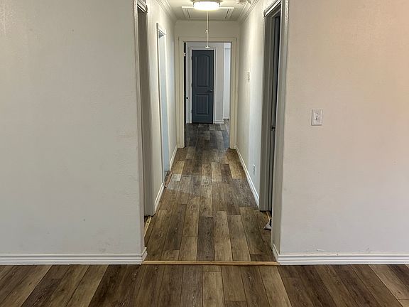 View of hallway from front door, bath on the left entry to kitchen and 3rd bedroom on the left, first bedroom on the right with primary bedroom at the end of the hallway