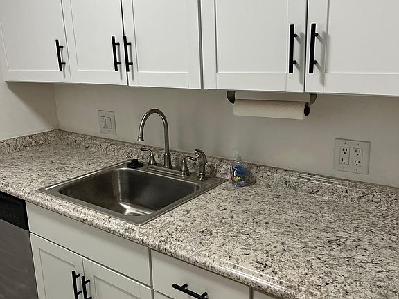 Large kitchen with new cabinets, sink and countertops.