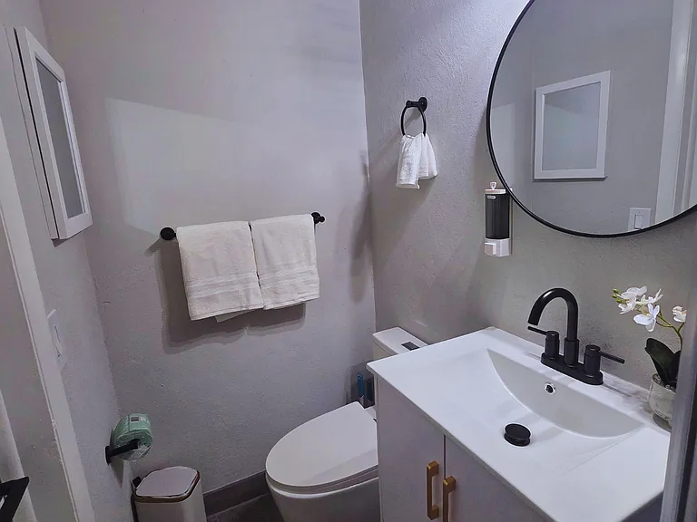 Modern full bathroom with a shower, toilet, sink, and mirror for your comfort.