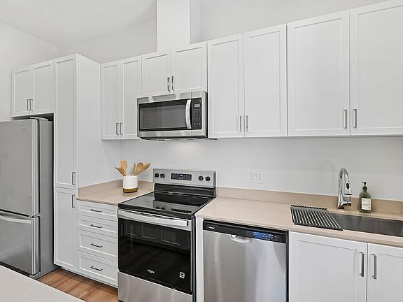 Freestanding Home kitchen with stainless steel appliances, white cabinetry, beige quartz countertops, and hard-surface flooring