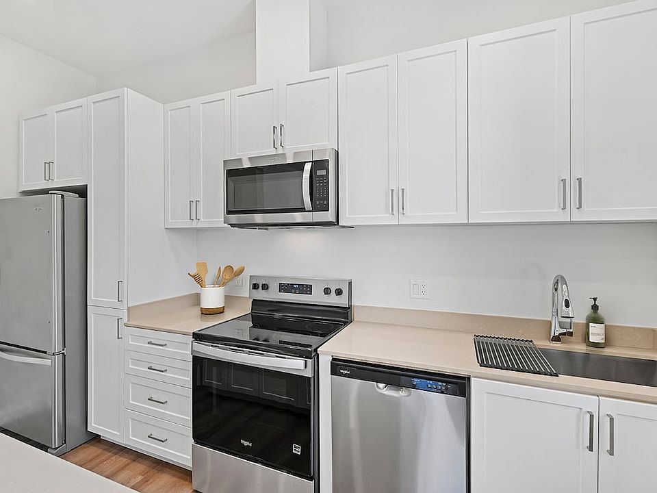 Coming Soon: Renovated Package II kitchen with stainless steel appliances, white cabinetry, beige quartz countertops, and hard-surface flooring