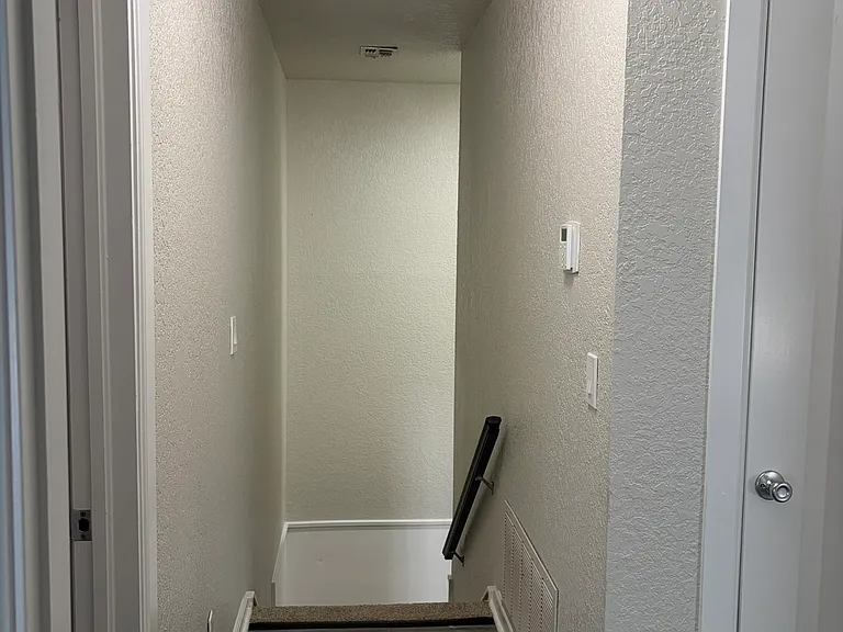 View of second floor hallway with stairway in background.