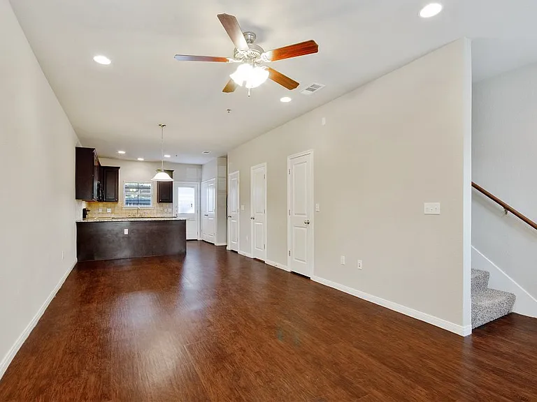 Spacious living area with wood style flooring and ceiling fans Spacious living area with wood style flooring and ceiling fans