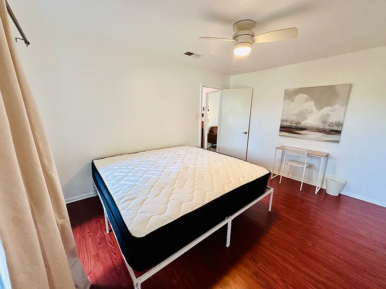 New king bed with mattress protector and pillow protectors. Workspace with desk.