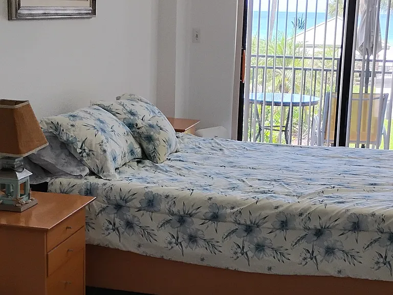 Master bedroom with a view of pool and beach as well as balcony access.