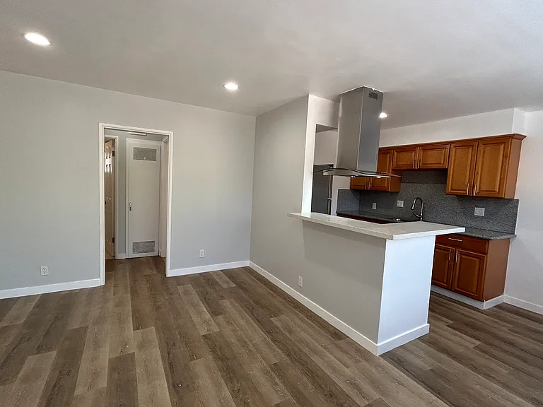 View from front door entrance, living room, kitchen on right, bedroom and bathroom entrance on the left.