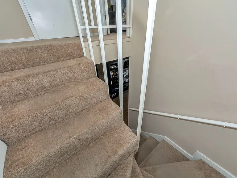 Townhome-style interior with carpeted staircase, upstairs landing, and convenient bedroom access at Watersong Villas Apartments.