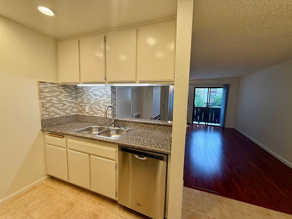 Kitchen with under counter lights and stainless steel sink and appliances, including full size refrigerator, dishwasher, stove, oven and microwave.