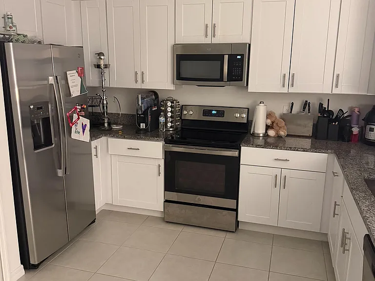 Efficient U-shaped kitchen with ample white cabinetry, generous counters, and stainless steel appliances for easy meal prep.