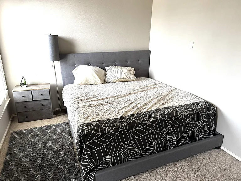 Furnished bedroom with a full-size bed, upholstered headboard, bedside storage, and soft carpet for added comfort.