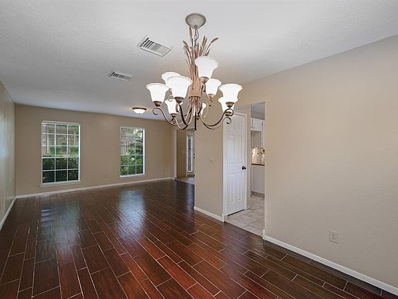 To the right of the entry are the formal living and formal dining rooms with hardwood flooring and a lovely wrought iron light fixture.