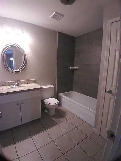 Guest bathroom with granite vanity, tile tub surrouns and linen closet
