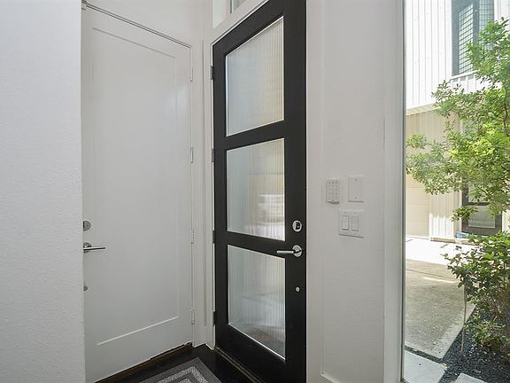 The entryway is light and bright with opaque glass door, gleaming hardwoods and the garage access.