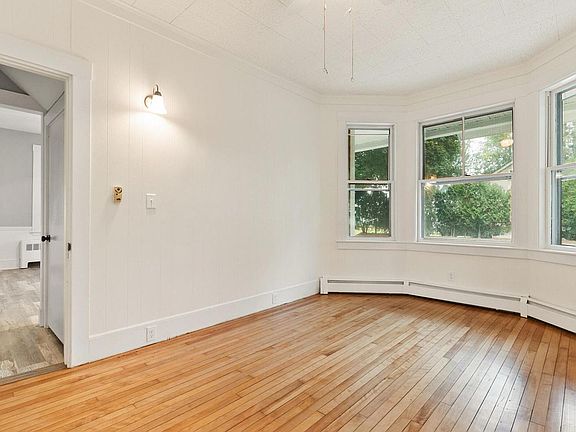 First floor bedroom with windows facing front and side of house; hardwood floors