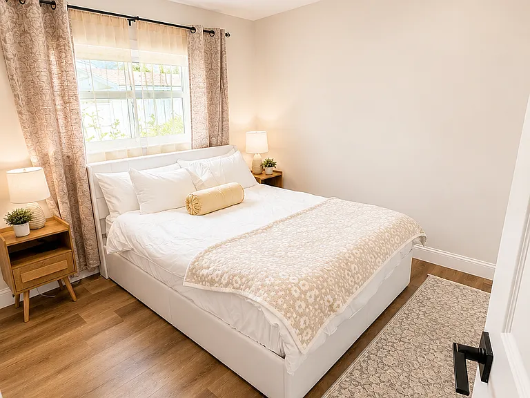Comfortable queen bedroom with updated decor, cozy bedding, blackout-style curtains, warm lighting, and a peaceful setup for restful Naples vacation stays.